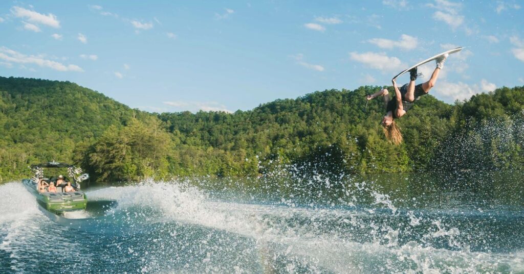 Malibu 23 MXZ with person doing a stunt on a wake board behind the boat